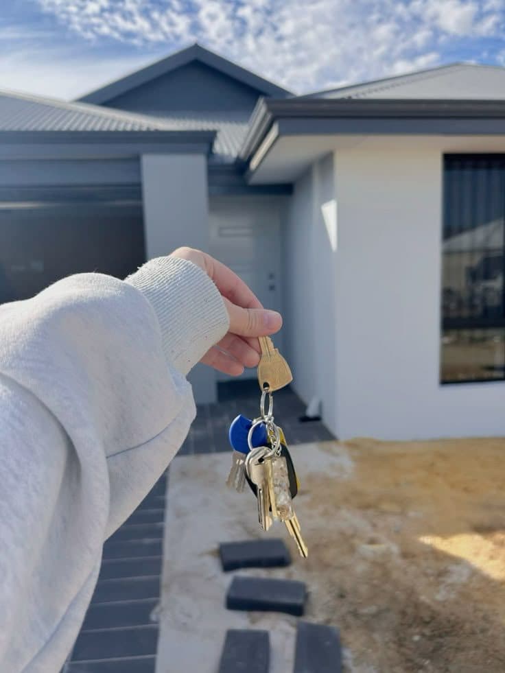 House keys held out in front of a home